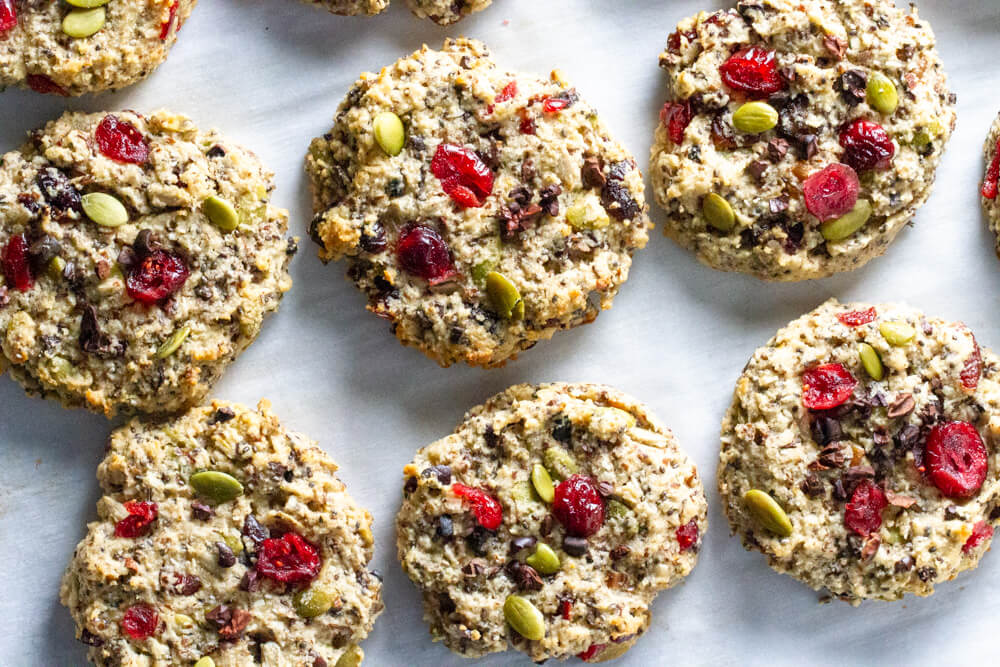 six cookies with dried cranberries and nuts on parchment paper
