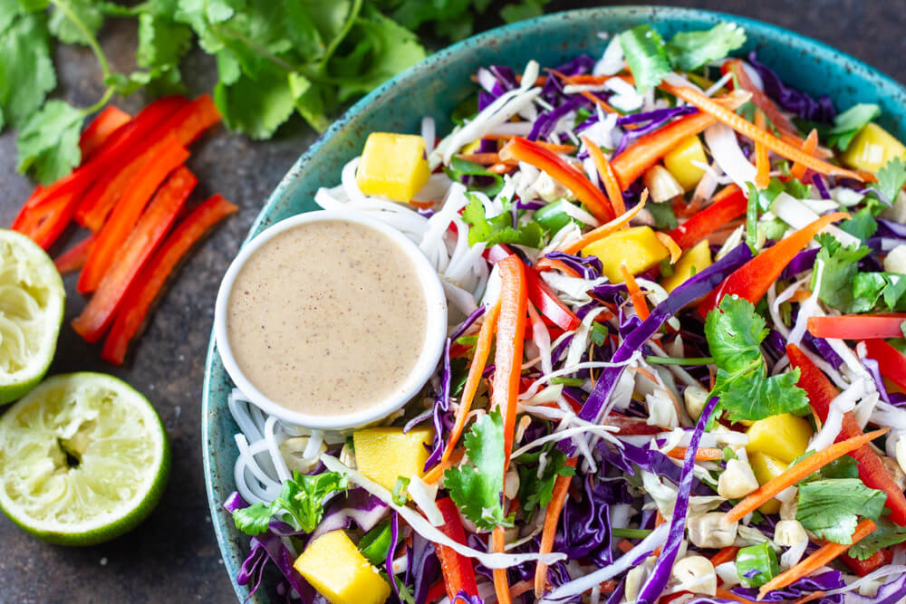 Thai Noodle Salad in a blue bowl with a side of dressing