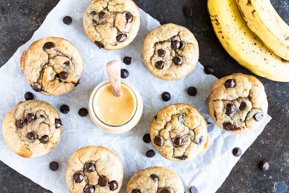 eight muffins with chocolate chips and a glass jar of peanut butter