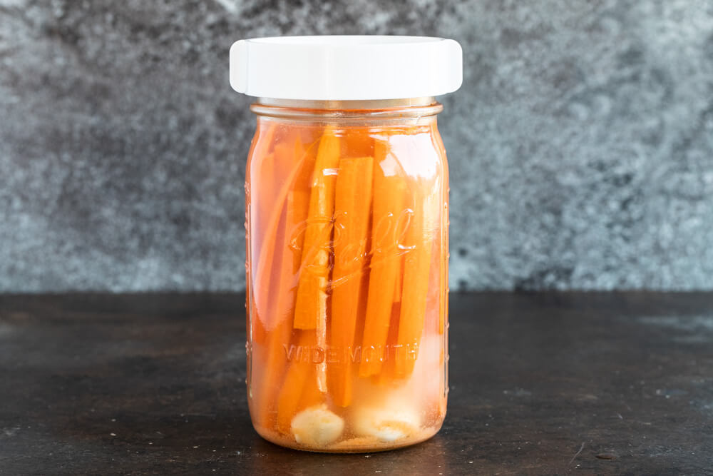mason jar with white lid and fermented carrot sticks