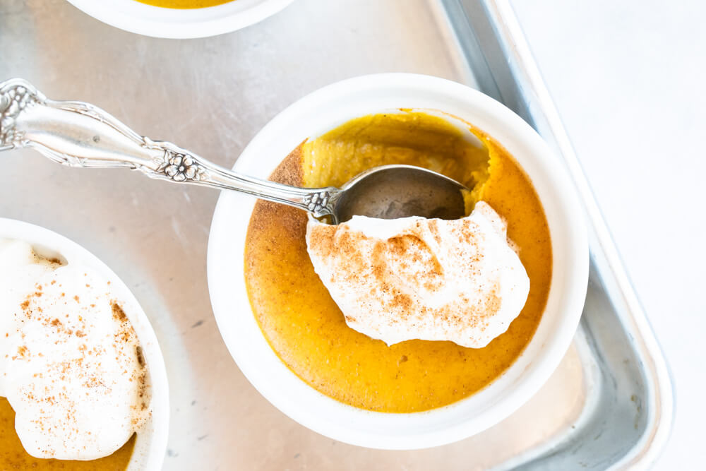 white bowl of pumpkin custard with silver spoon