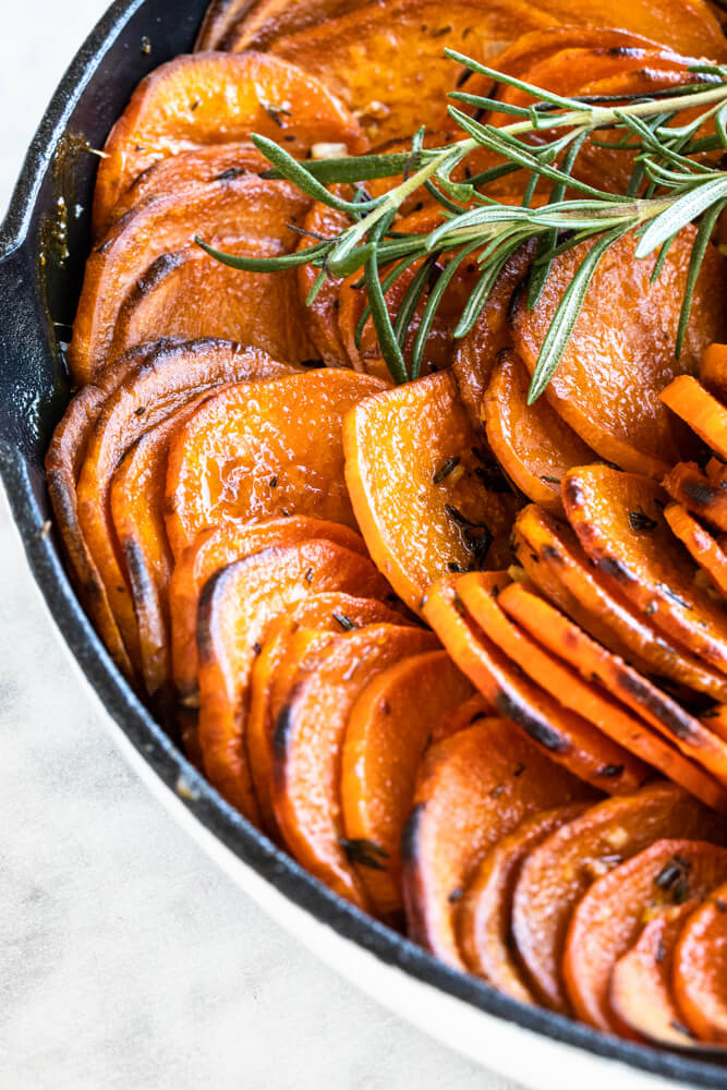 close up of sweet potatoes cooked in butter with fresh rosemary