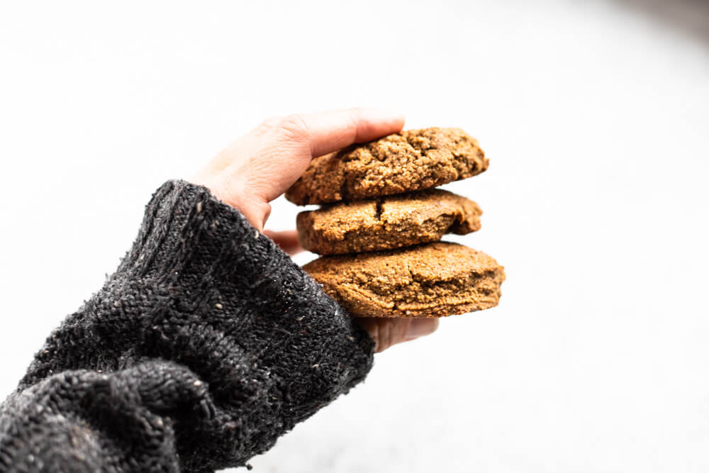 hand with grey sweater holding three cookies