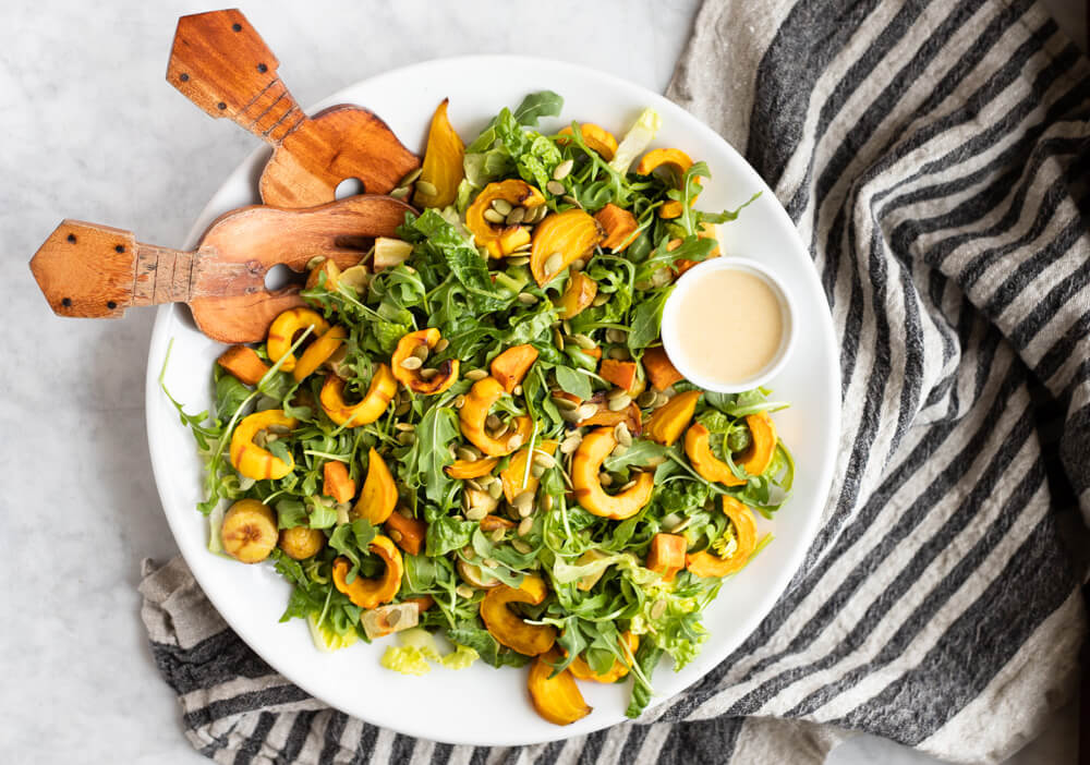 winter salad on white plate with wooden tongs