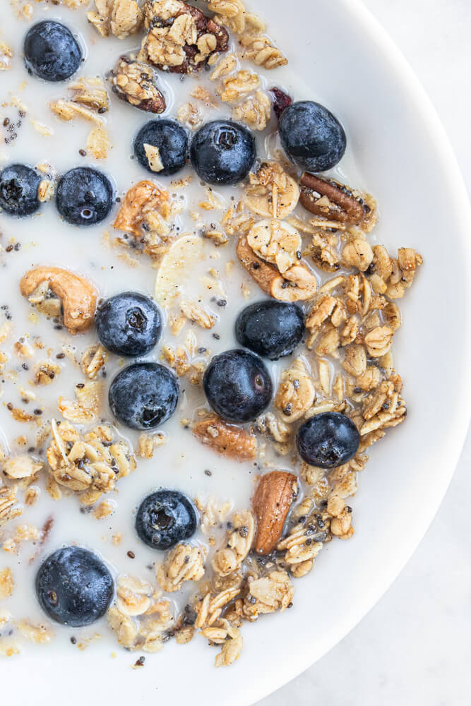 white bowl with granola and milk
