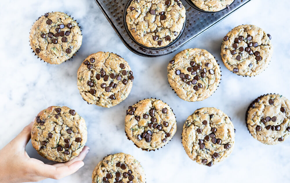 hand reaching for zucchini muffins