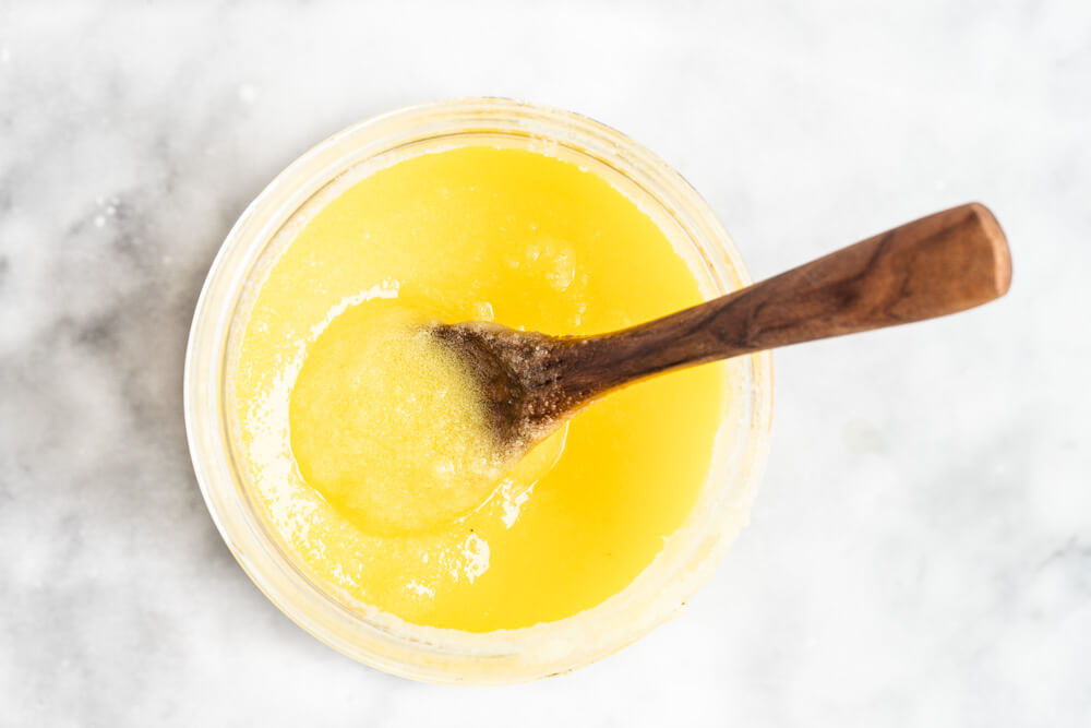 glass jar of ghee and a wooden spoon