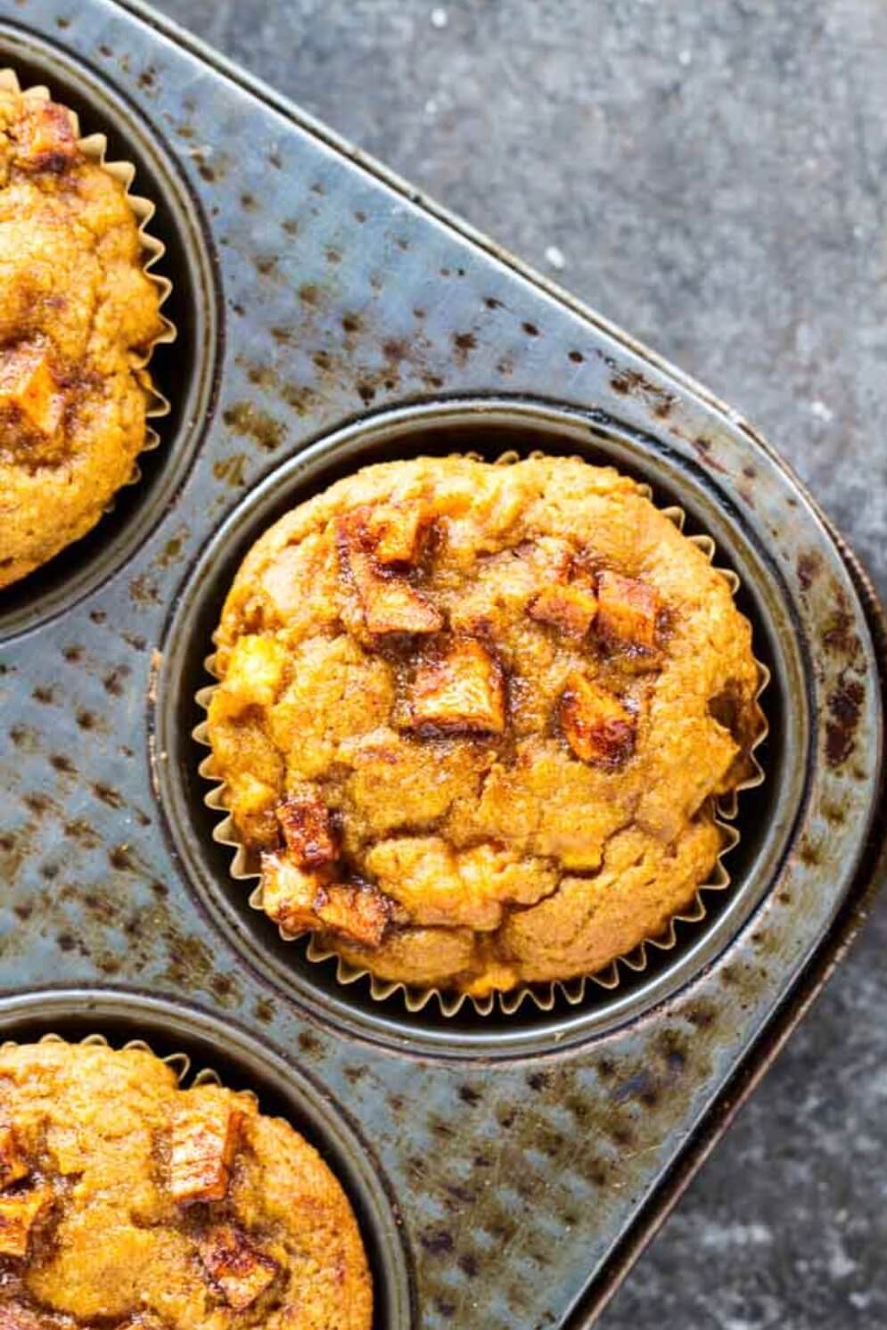 close up of an orange muffin with apples chunks on top