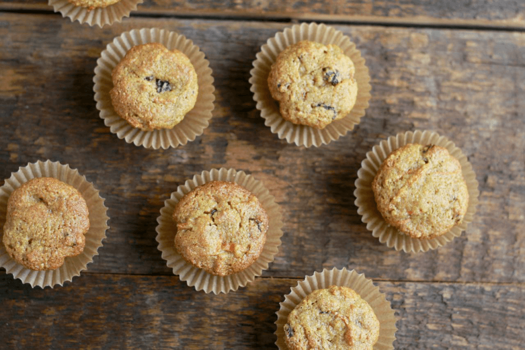 small Carrot Ginger Coconut Muffins in muffin wrappers on wooden table